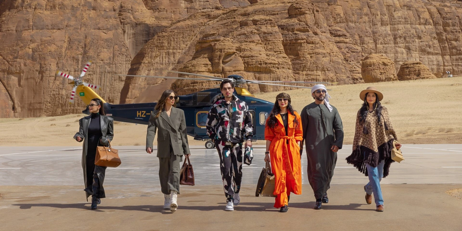 5 people walking away from a helicopter, carrying bags